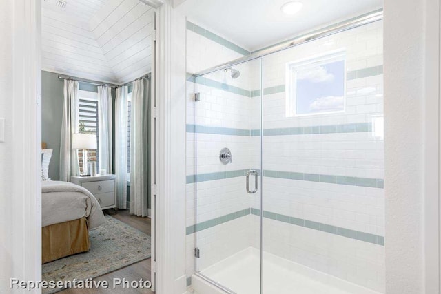 bathroom with a stall shower, ensuite bath, and wood finished floors
