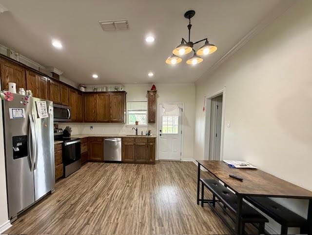 kitchen featuring a sink, appliances with stainless steel finishes, ornamental molding, and wood finished floors