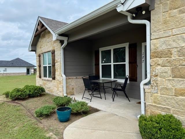 view of property exterior featuring a lawn, a patio, and stone siding
