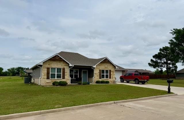 view of front of property featuring driveway, a front yard, central AC unit, a garage, and stone siding