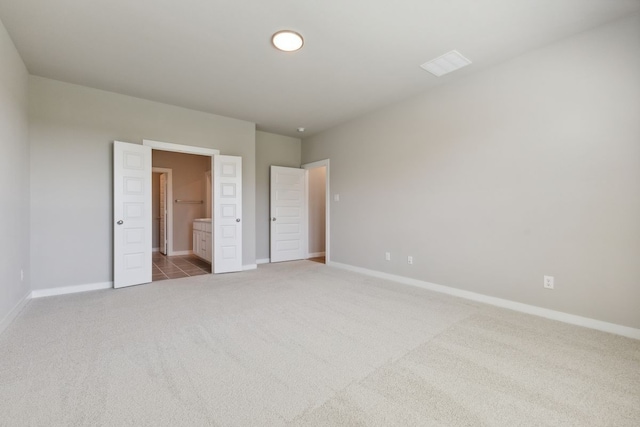 unfurnished bedroom featuring carpet flooring, baseboards, visible vents, and ensuite bathroom