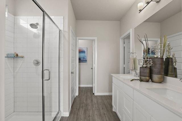 full bathroom featuring baseboards, a shower stall, a sink, and wood finished floors