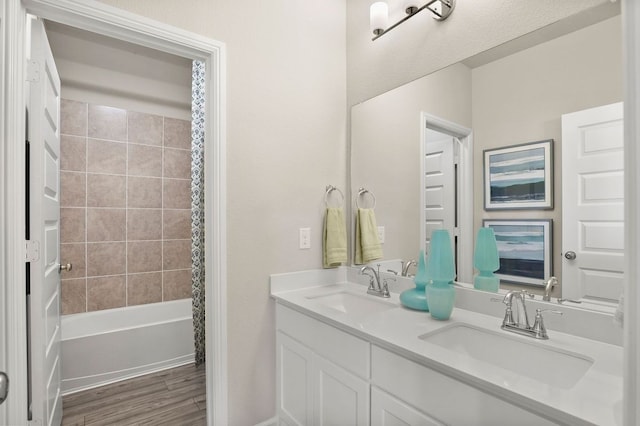 full bathroom featuring double vanity, shower / bathtub combination with curtain, a sink, and wood finished floors