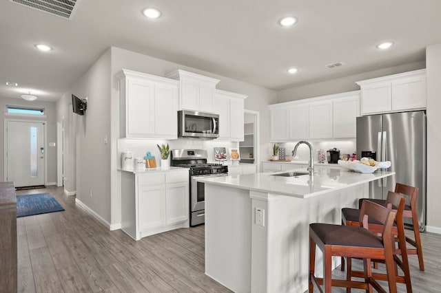 kitchen featuring visible vents, a sink, a kitchen bar, and stainless steel appliances