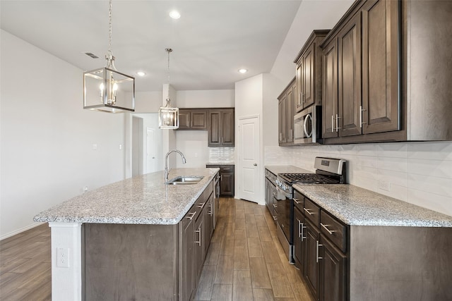 kitchen with decorative backsplash, dark brown cabinetry, dark wood-style floors, a sink, and appliances with stainless steel finishes
