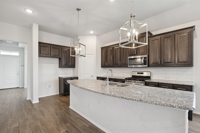 kitchen with an inviting chandelier, dark brown cabinetry, dark wood-style floors, a sink, and stainless steel appliances