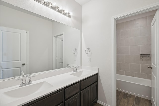 full bath with double vanity, a sink, wood finished floors, and bathing tub / shower combination