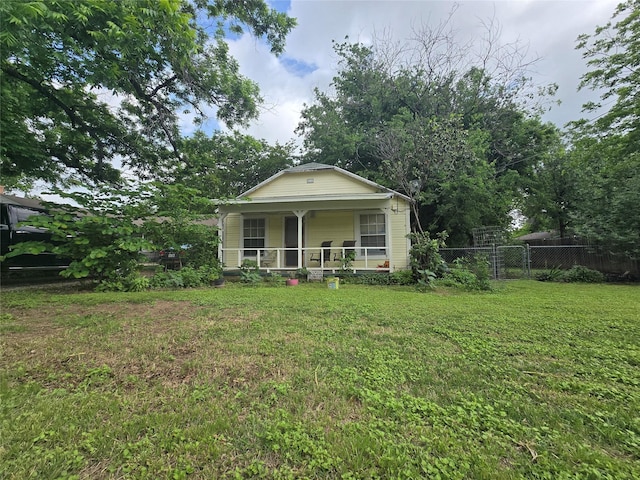 bungalow-style home featuring covered porch, fence, and a front lawn