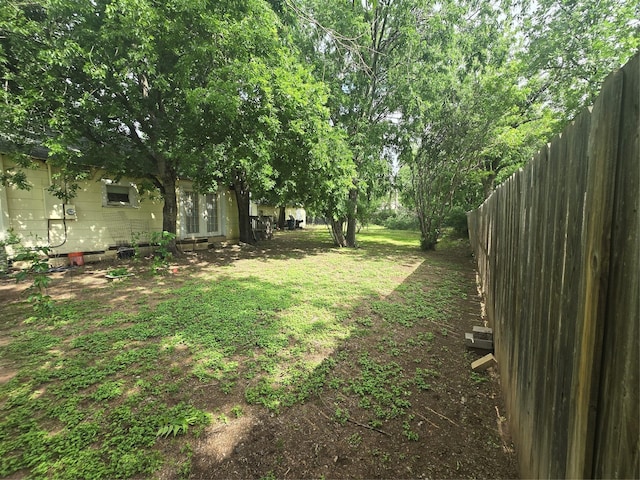 view of yard featuring fence and french doors