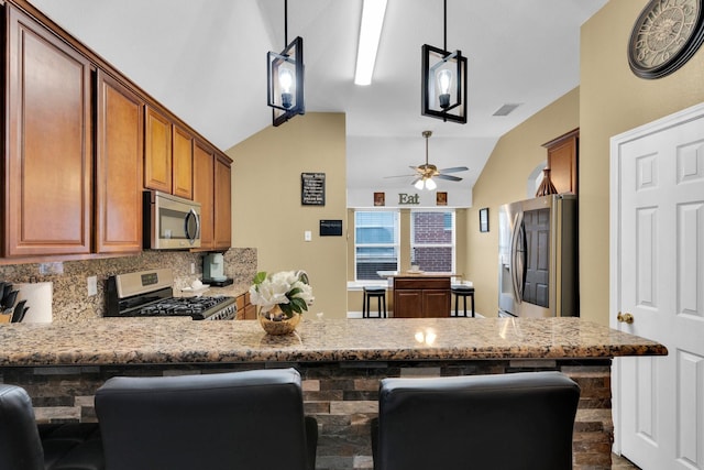 kitchen featuring a peninsula, lofted ceiling, ceiling fan, backsplash, and stainless steel appliances