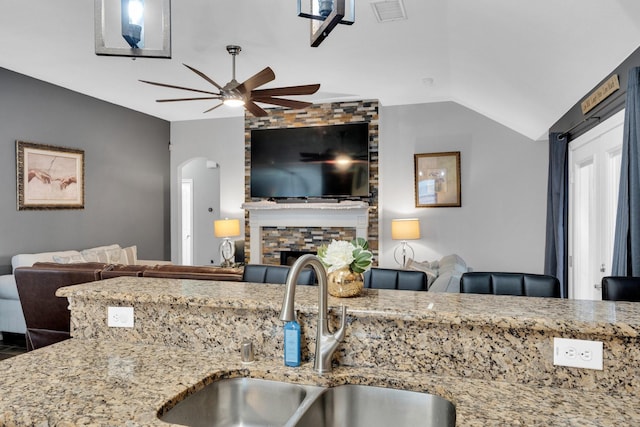 kitchen featuring ceiling fan, visible vents, arched walkways, a sink, and open floor plan