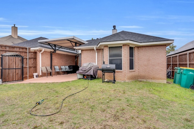 back of property featuring a chimney, brick siding, a fenced backyard, a yard, and a patio