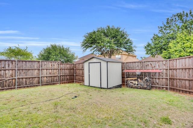 view of yard featuring a storage unit, a fenced backyard, and an outdoor structure