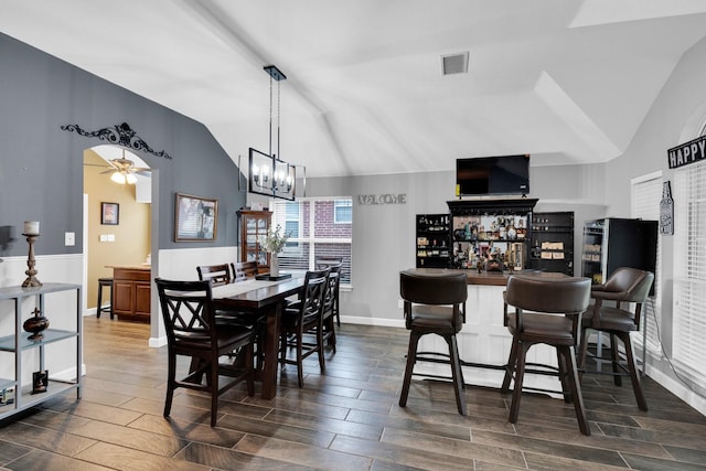 dining area featuring visible vents, wood tiled floor, ceiling fan with notable chandelier, and vaulted ceiling