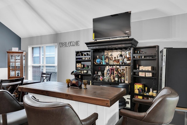 bar featuring a dry bar, lofted ceiling, and freestanding refrigerator