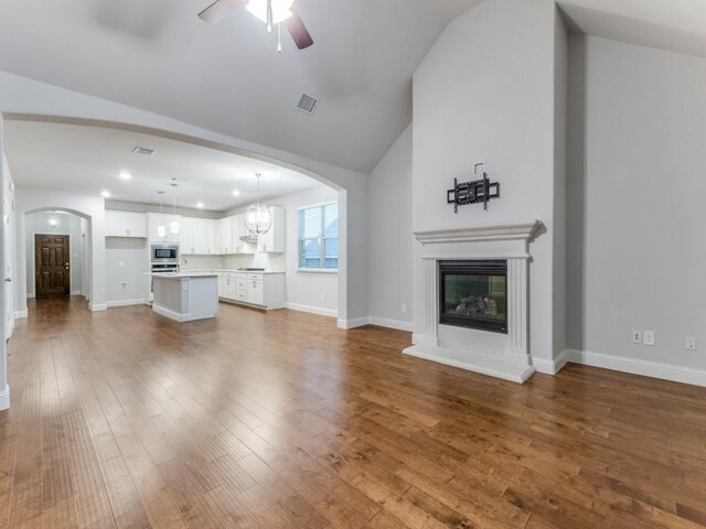 unfurnished living room featuring visible vents, arched walkways, ceiling fan, and lofted ceiling