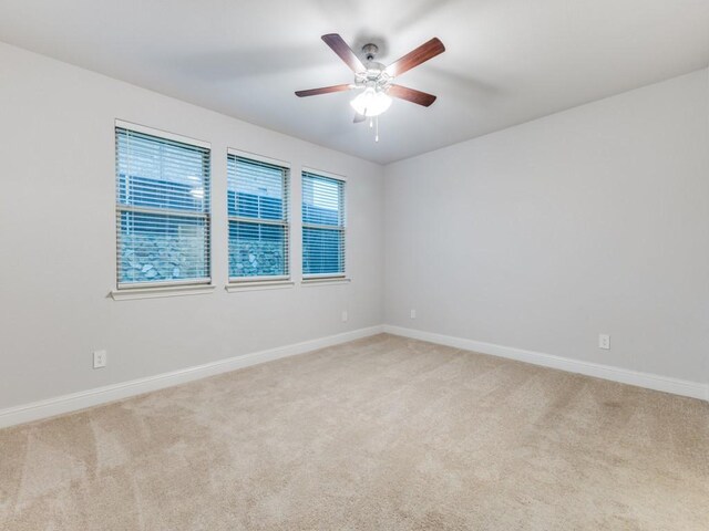 spare room featuring a ceiling fan, baseboards, and light colored carpet