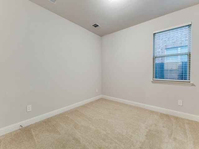 spare room featuring carpet flooring, baseboards, and visible vents