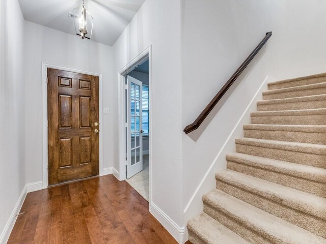 foyer entrance with baseboards, dark wood finished floors, and stairs
