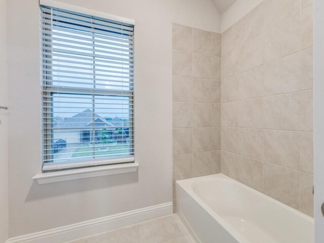 bathroom with a washtub, baseboards, and tile patterned flooring