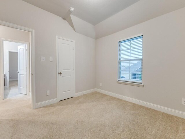 unfurnished room with baseboards, lofted ceiling, and light carpet