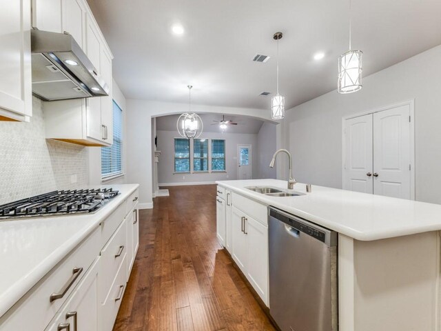 kitchen featuring appliances with stainless steel finishes, tasteful backsplash, a sink, extractor fan, and dark wood-type flooring
