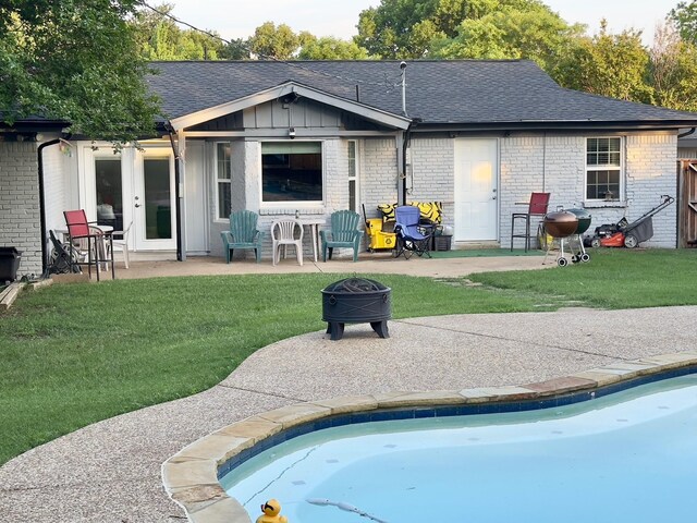 back of house with brick siding, a patio area, and roof with shingles