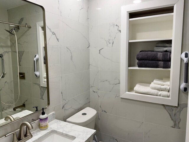 bathroom with vanity, walk in shower, toilet, and tile walls