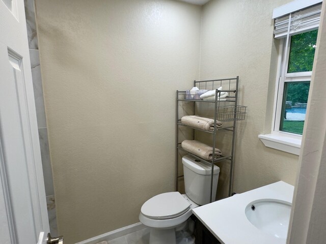 bathroom featuring vanity, baseboards, a textured wall, and toilet