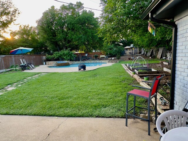 view of yard with a fenced backyard, a patio area, a pool with connected hot tub, and a garden