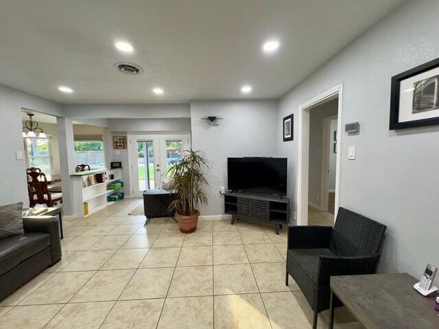 living area with recessed lighting, light tile patterned flooring, visible vents, and french doors