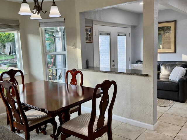 dining space featuring baseboards, a textured wall, and light tile patterned floors