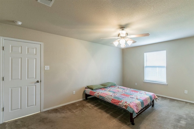 carpeted bedroom featuring a ceiling fan, baseboards, visible vents, and a textured ceiling