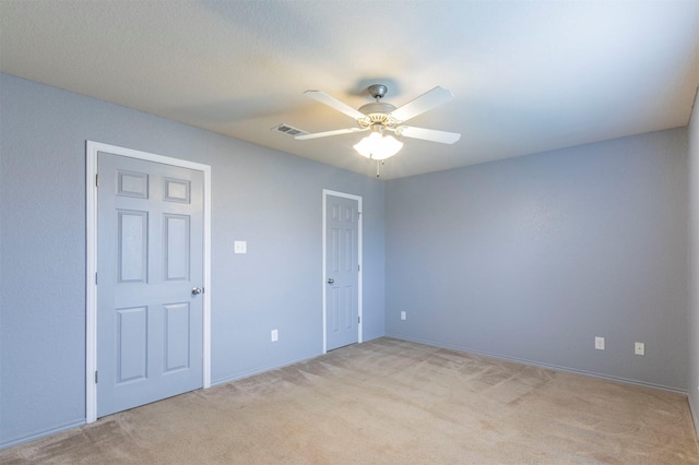 unfurnished bedroom featuring baseboards, a ceiling fan, light colored carpet, and visible vents