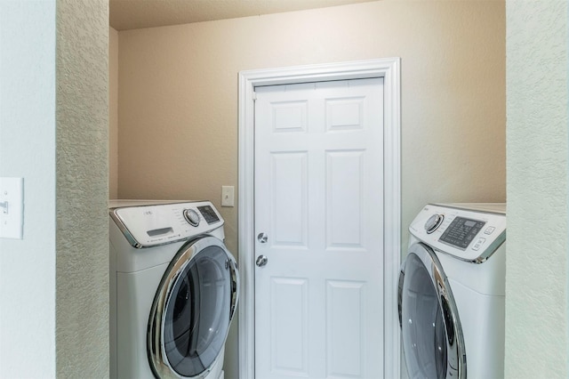 laundry area with a textured wall and washer and dryer