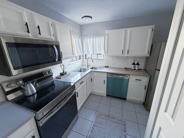 kitchen with tasteful backsplash, a sink, light countertops, white cabinets, and stainless steel appliances