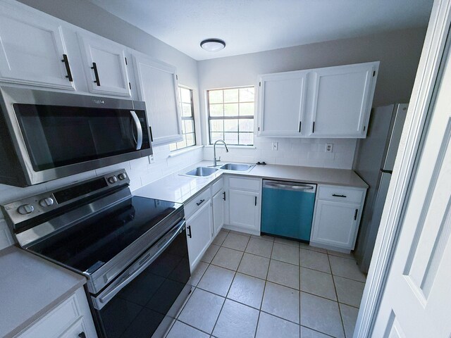kitchen featuring stainless steel appliances, white cabinetry, a sink, and tasteful backsplash