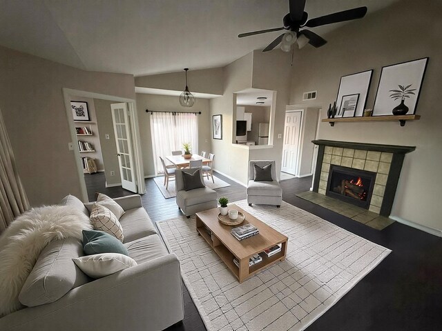 living room with ceiling fan, baseboards, lofted ceiling, a tile fireplace, and visible vents