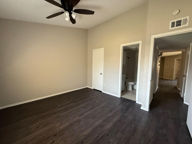 unfurnished bedroom with connected bathroom, dark wood finished floors, baseboards, lofted ceiling, and visible vents