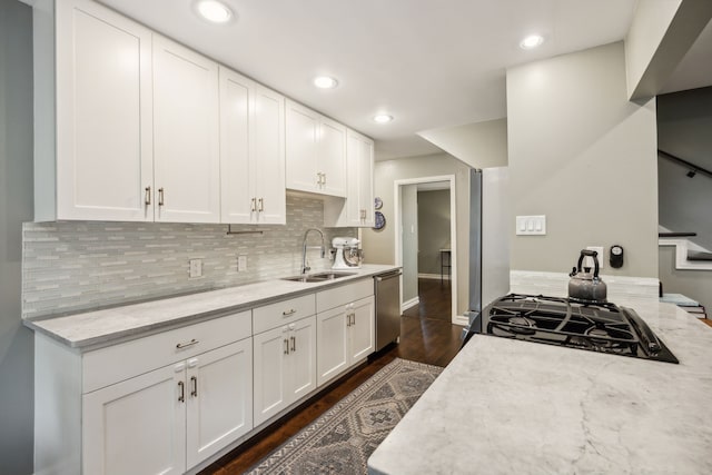 kitchen with stainless steel dishwasher, decorative backsplash, dark wood-type flooring, white cabinetry, and a sink