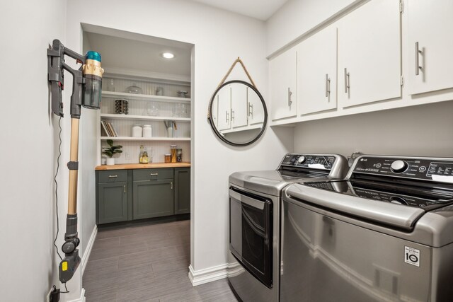 washroom featuring separate washer and dryer, cabinet space, baseboards, and wood finished floors