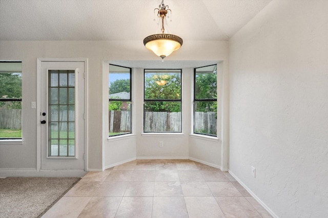 entryway featuring baseboards, a textured wall, and light tile patterned floors