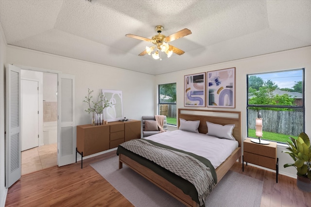 bedroom featuring a textured ceiling, wood finished floors, and multiple windows