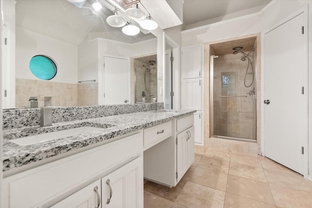 bathroom with double vanity, a sink, a stall shower, and tile patterned floors
