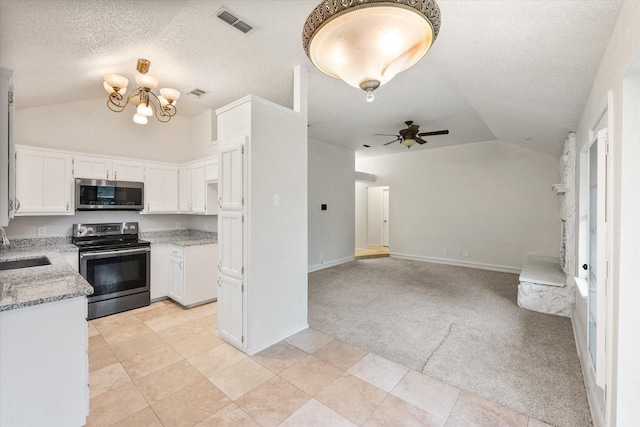 kitchen featuring lofted ceiling, light carpet, a textured ceiling, a sink, and stainless steel appliances