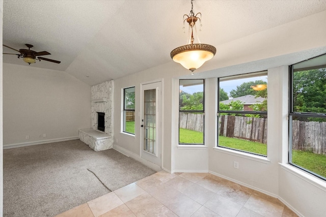 interior space featuring a stone fireplace, plenty of natural light, and lofted ceiling