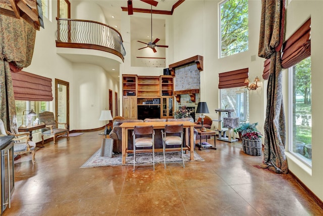 living area with a ceiling fan, a high ceiling, and a wealth of natural light