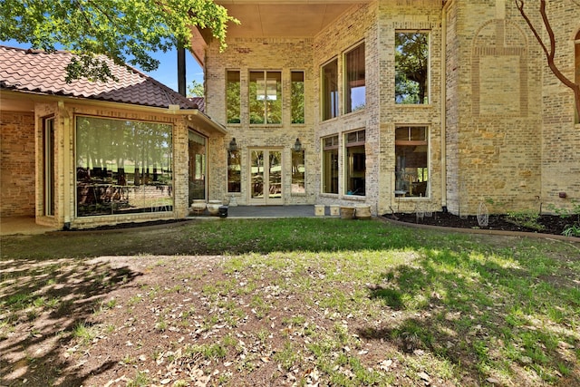 rear view of property featuring a tiled roof and a yard