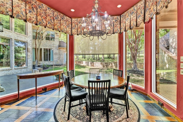 sunroom / solarium featuring plenty of natural light, stone tile floors, and an inviting chandelier