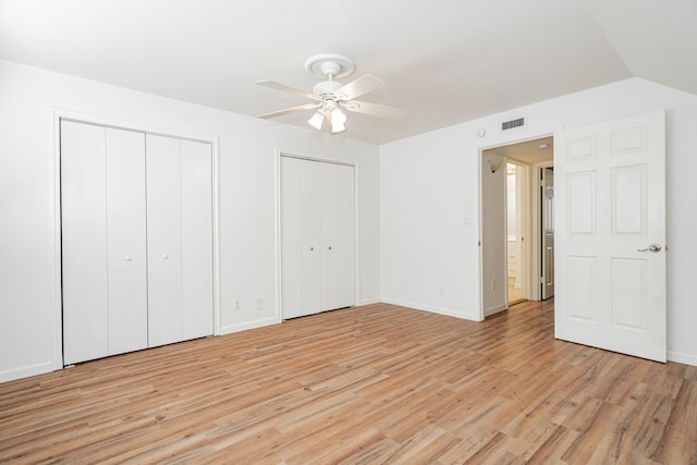 unfurnished bedroom with light wood-style floors, baseboards, ceiling fan, and two closets
